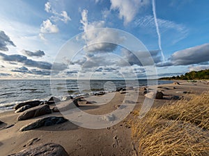 Seascape image of the sea with cloudy sky before sunset,  stones and  of light before sunset, beautiful sunny day and quiet sea.