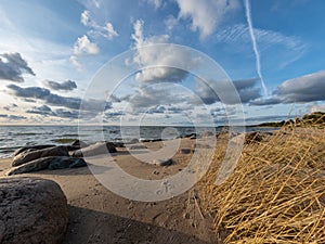 Seascape image of the sea with cloudy sky before sunset,  stones and  of light before sunset, beautiful sunny day and quiet sea.