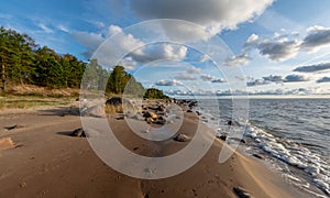 Seascape image of the sea with cloudy sky before sunset,  stones and  of light before sunset, beautiful sunny day and quiet sea.