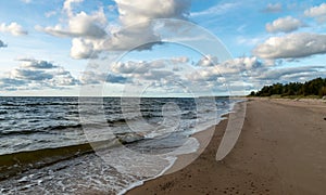 Seascape image of the sea with cloudy sky before sunset,  stones and  of light before sunset, beautiful sunny day and quiet sea.