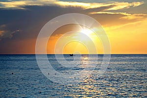 seascape image with shiny sea and speedboat over cloudy sky and sun during sunset in Cozumel, Mexico