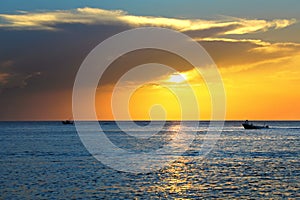 seascape image with shiny sea and speedboat over cloudy sky and sun during sunset in Cozumel, Mexico