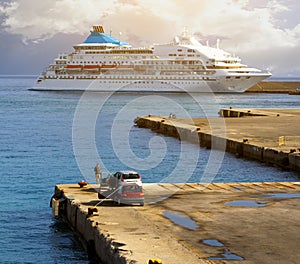 Seascape. A large white cruise ship stands in the tourist sea port at sunset, Rhodes, Greece. cars with fishermen in the