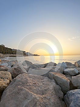 Seascape with Malaga and sunrise sunlight. Sandy beach of the Mediterranean Sea and walking stone pier in Playa de la Caleta,