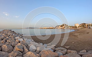 Seascape with Malaga and sunrise sunlight. Sandy beach of the Mediterranean Sea and walking stone pier in Playa de la Caleta, photo