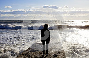 Seascape. Marine landscape with the figure of a woman. Wave on the sea breakwater.