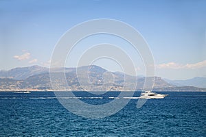 Seascape with mountains at the background and white yacht