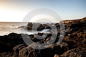 seascape with mountains and rocks, long exposure and waves that become foam. Image for black and white backgrounds. Tenerife