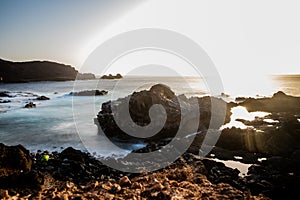 seascape with mountains and rocks, long exposure and waves that become foam. Image for black and white backgrounds. Tenerife