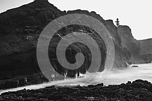 seascape with mountains and rocks, long exposure and waves that become foam. Image for black and white backgrounds. Tenerife