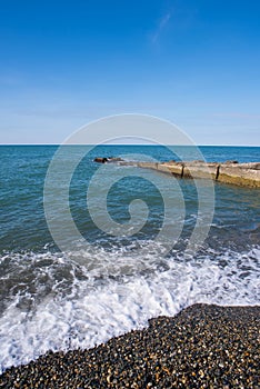Seascape pebble beach, concrete pier. Marine background