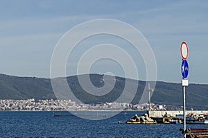 Seascape of pier with cross at end for fishing boat in the Black Sea and Balkan mountain near ancient city Nessebar