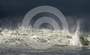 Seascape. Powerful ocean wave on the surface of the ocean. Wave breaks on a shallow bank. Stormy weather, stormy clouds sky