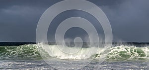 Seascape. Powerful ocean wave on the surface of the ocean. Wave breaks on a shallow bank. Stormy weather, stormy clouds sky