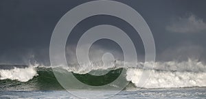 Seascape. Powerful ocean wave on the surface of the ocean. Wave breaks on a shallow bank. Stormy weather, stormy clouds sky