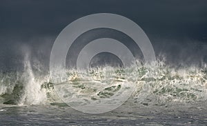 Seascape. Powerful ocean wave on the surface of the ocean. Wave breaks on a shallow bank. Stormy weather, stormy clouds sky