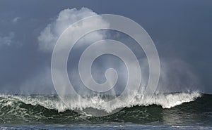 Seascape. Powerful ocean wave on the surface of the ocean. Wave breaks on a shallow bank. Stormy weather, stormy clouds sky