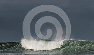 Seascape. Powerful ocean wave on the surface of the ocean. Wave breaks on a shallow bank. Stormy weather, stormy clouds sky