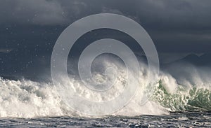 Seascape. Powerful ocean wave on the surface of the ocean. Wave breaks on a shallow bank. Stormy weather, stormy clouds sky