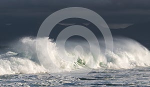 Seascape. Powerful ocean wave on the surface of the ocean. Wave breaks on a shallow bank. Stormy weather, stormy clouds sky