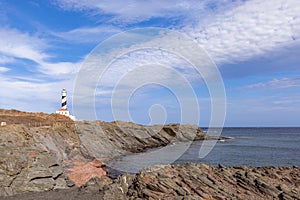 Seascape with a quiet sea bay and a lighthouse Faro de Favaritx on the island of Menorca, Balearic islands, Spain