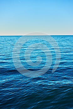 Seascape with rippled sea water, horizon and blue sky