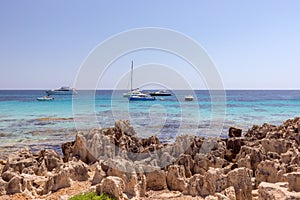 Seascape with rocky beach and emerald sea with yachts. Ibiza island. Balearic Islands, Spain