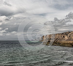 Seascape. rocky shore in the sea, wild beach and mountains, the rock goes into the sea view, wild landscape. clouds over the sea
