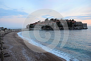 Seascape - sandy beaches of the Adriatic Sea against the backdrop of the sunset, clouds, and a group of hotels Aman Sveti Stefan,