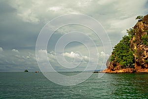 Seascape scenic red cliff island with cloudy sky