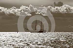 Seascape with a schooner in the roadstead on a sunny and cloudy day. Monochrome, sepia