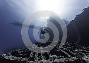 Seascape of a scuba diver swimming in the distance over a very large ship wreck