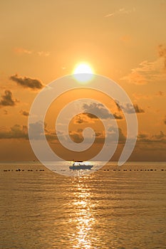 Seascape of sea during sunrise with silhouette of small boat