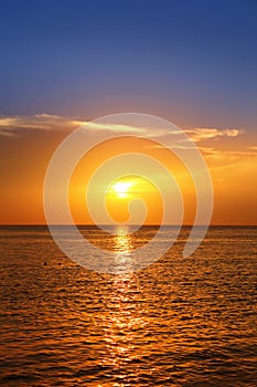 Seascape with shiny sea over cloudy sky and sun during sunset in Cozumel, Mexico