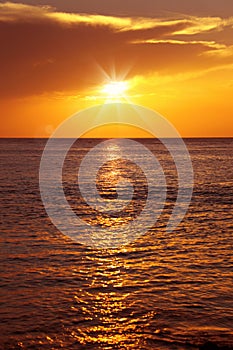 seascape with shiny sea over cloudy sky and sun during sunset in Cozumel, Mexico