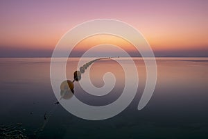 Seascape showing a pink sunrise in dim light over the calm waters of the Mar Menor, in the Region of Murcia, Spain