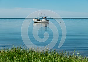 Seascape with a small boat in calm water, sunny summer day, reflections in the water, Sorve Peninsula, Estonia