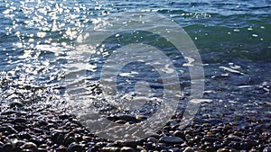 Seascape. small waves are hitting the shore on a pebbly beach.