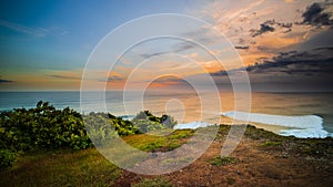 Seascape. Spectacular view from Uluwatu cliff in Bali. Sunset time. Blue hour. Ocean with motion foam waves. Cloudy sky. Nature