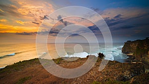 Seascape. Spectacular view from Uluwatu cliff in Bali. Sunset time. Blue hour. Ocean with motion foam waves. Cloudy sky. Nature