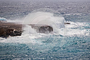 Seascape during a storm. Sea with blue water and big waves, waves hitting the rocks with big splashes