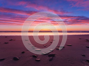 Seascape during sunrise. Bright clouds on the sky. Lines of sand on the seashore.