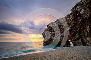 Seascape at sunrise. The sun rises over the sea and illuminates it. Long exposure. A large rock with an arch through which the