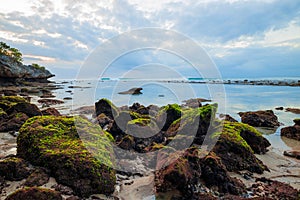 Seascape. Sunset at the beach. Ocean low tide. Rocks with green seaweeds. Cloudy sky. Horizontal background banner. Thomas beach,