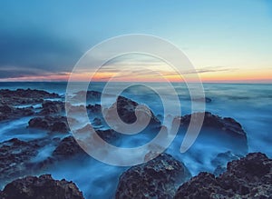 Seascape with sunset and rocks in a calm sea water