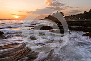 Seascape in sunset with strong wave at Tanah Lot Temple in Bali, Indonesia. Famous landmark tourist attraction and travel destinat