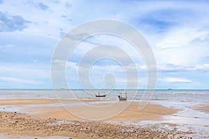 Seascape in Thailand with fishing boats on low tide beach.