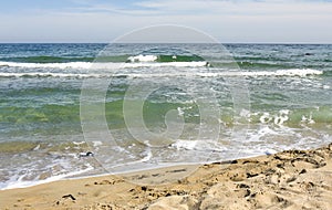 Seascape, turgouise sea with little waves and part of sandy beach, photograph processed with special effect of