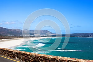 Seascape, turquoise ocean water waves, blue sky, white sand lonely beach panorama Chapmans Peak Drive road, South Africa coast t