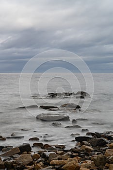 seascape under a cloudy sky with waves and rocks in the foreground